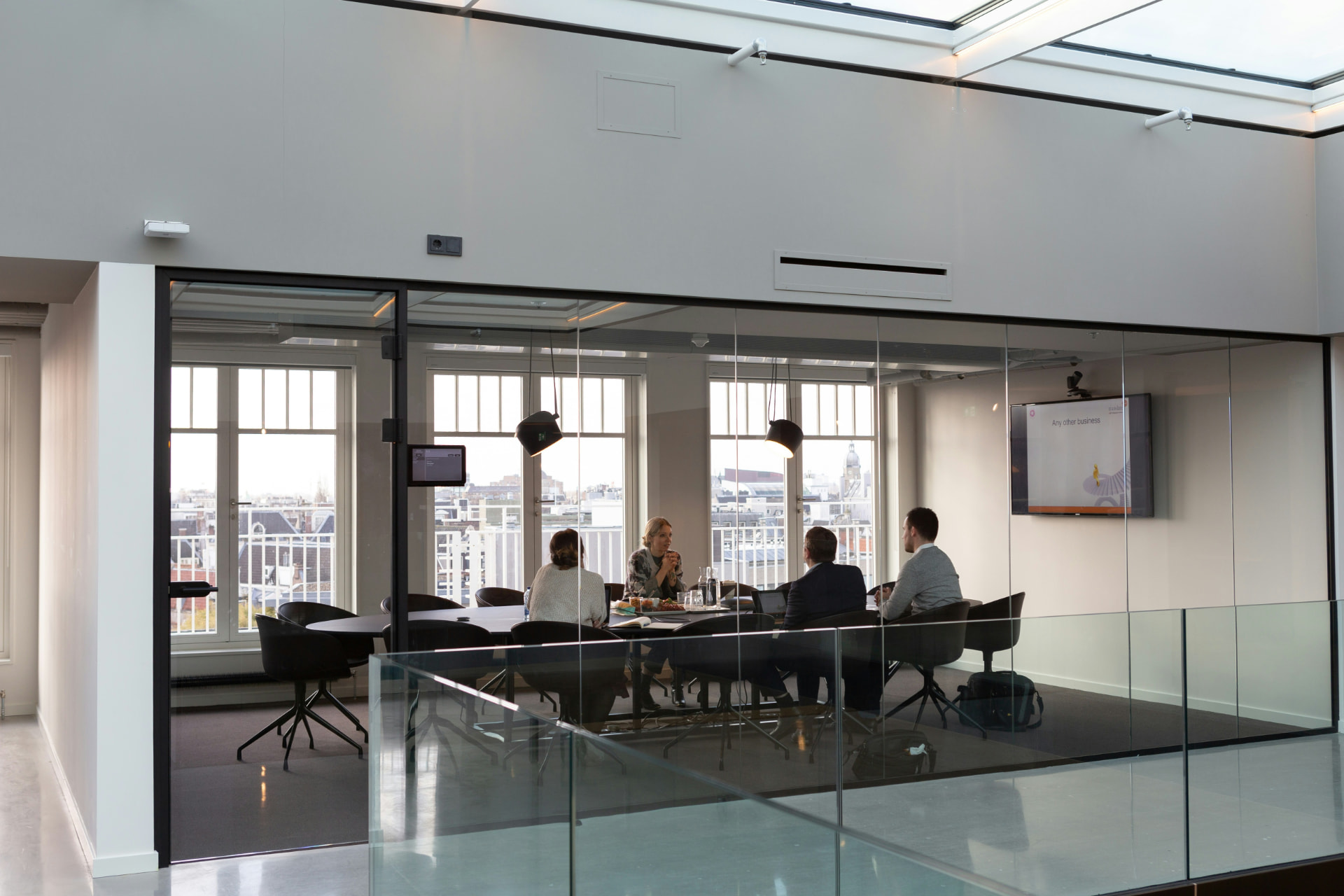 A small group in conversation around a table inside a glass walled meeting room